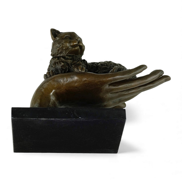 Escultura de bronce de un gato descansando en una mano