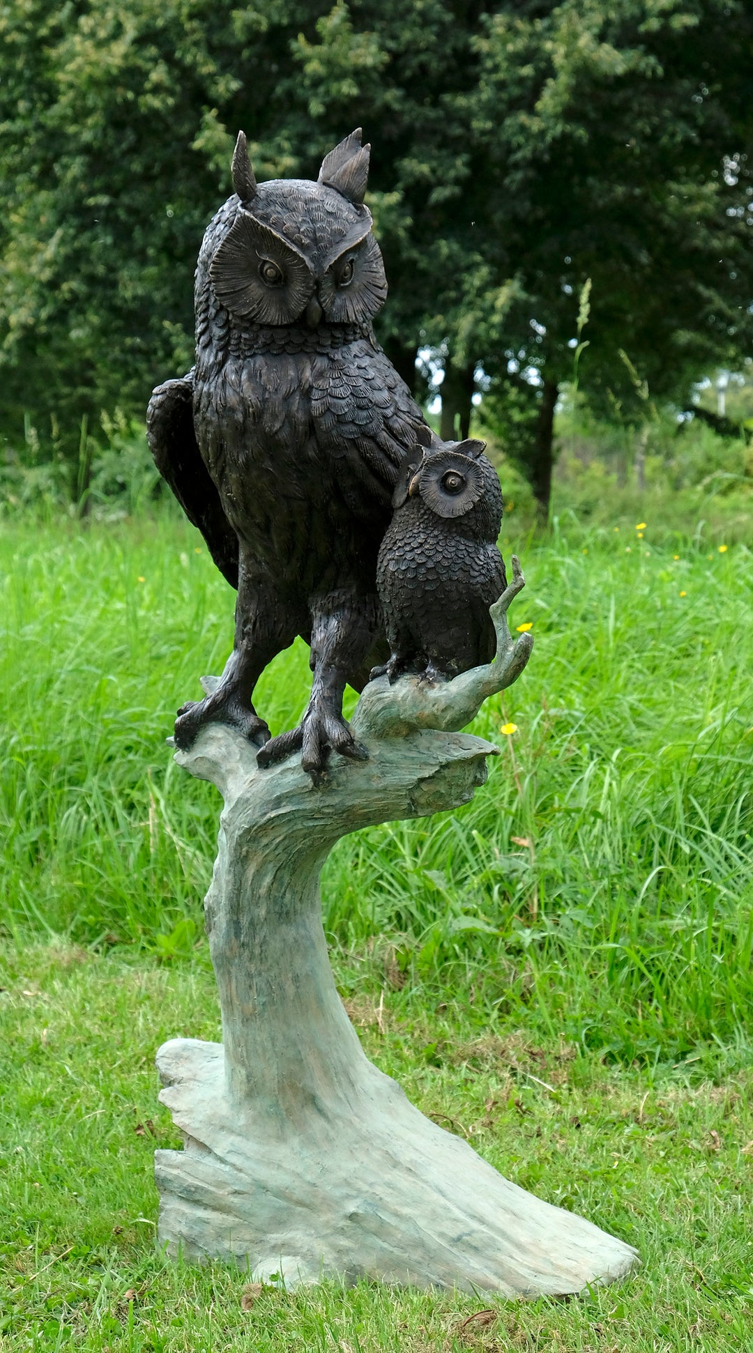 Large bronze sculpture of an owl with owlet on a tree trunk