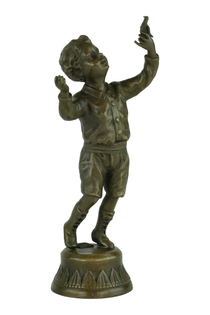 Bronze sculpture of a young boy fascinated by a bird