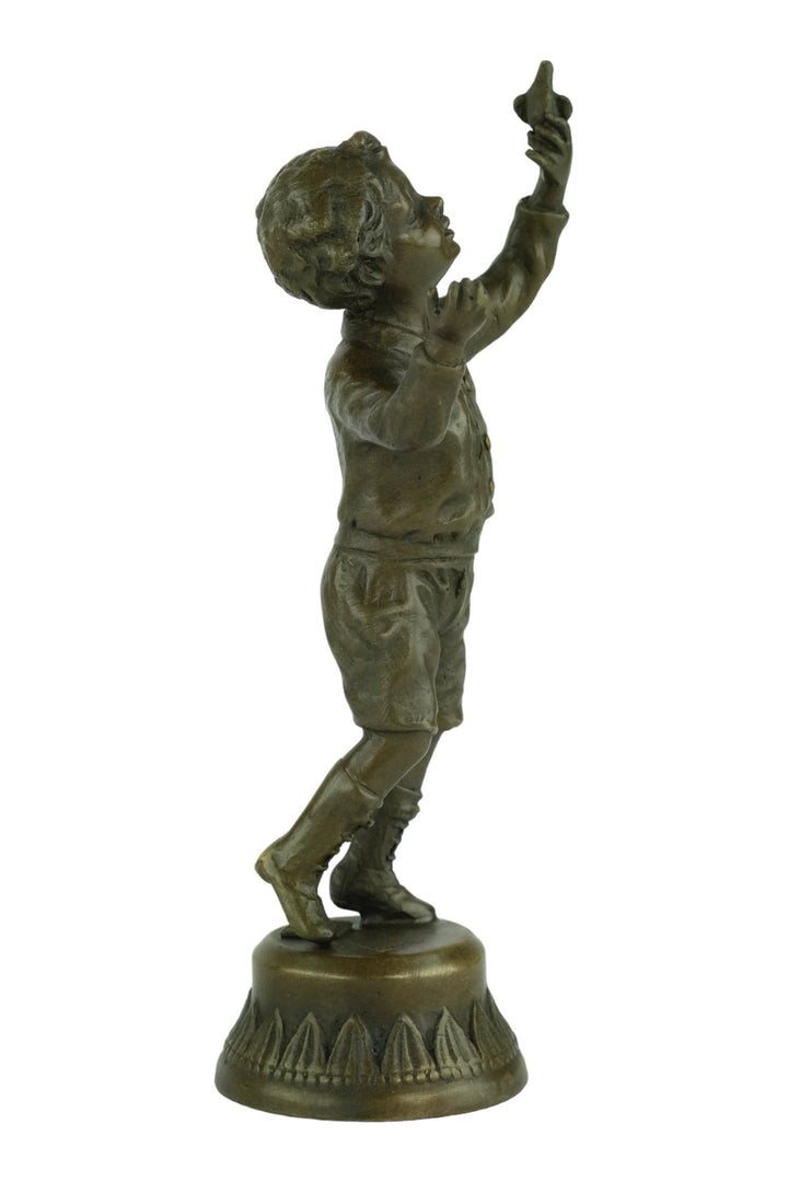 Bronze sculpture of a young boy fascinated by a bird