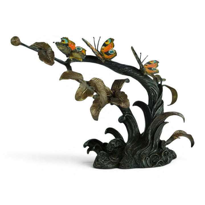 Escultura de bronce de tres mariposas en una rama