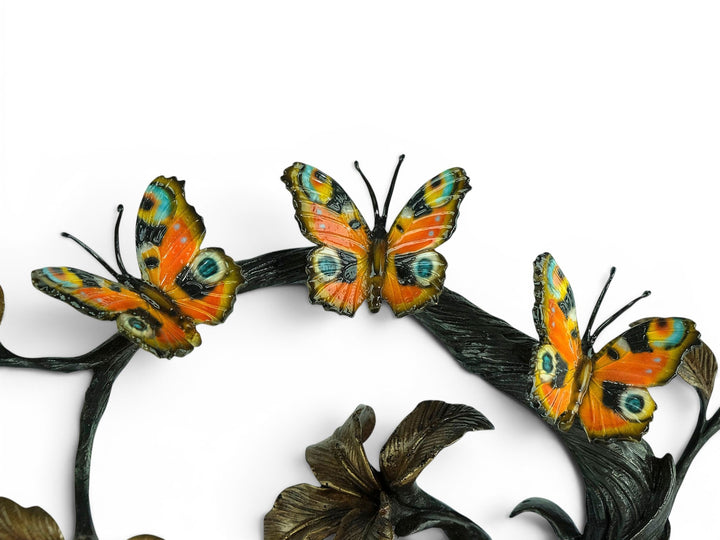 Escultura de bronce de tres mariposas en una rama