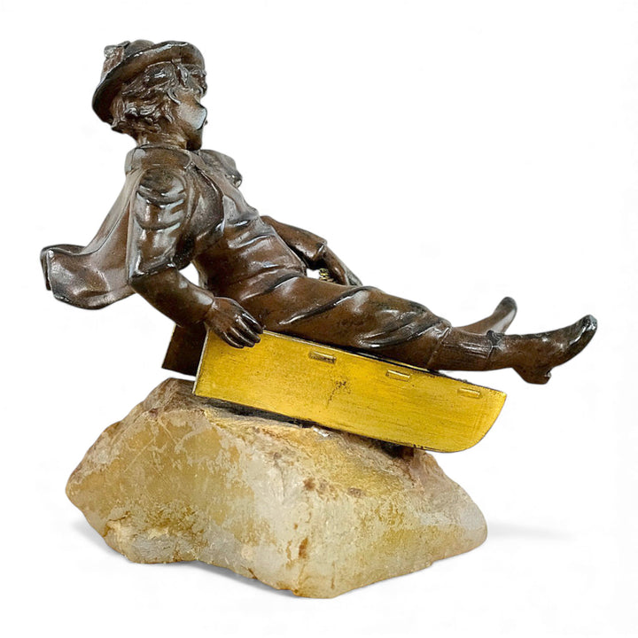 Escultura antigua de bronce de un niño en un trineo.
