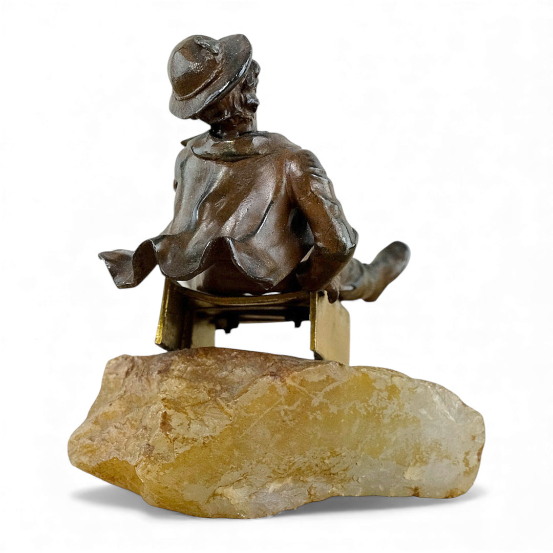 Escultura antigua de bronce de un niño en un trineo.
