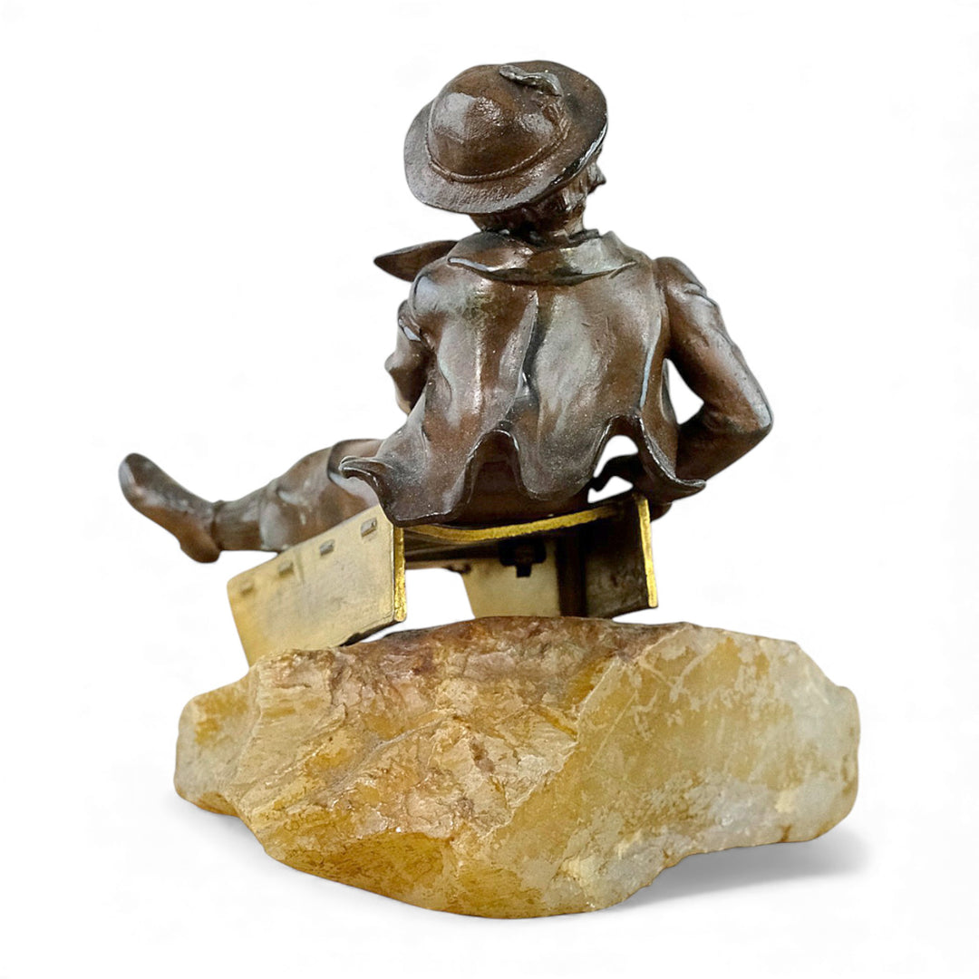 Escultura antigua de bronce de un niño en un trineo.