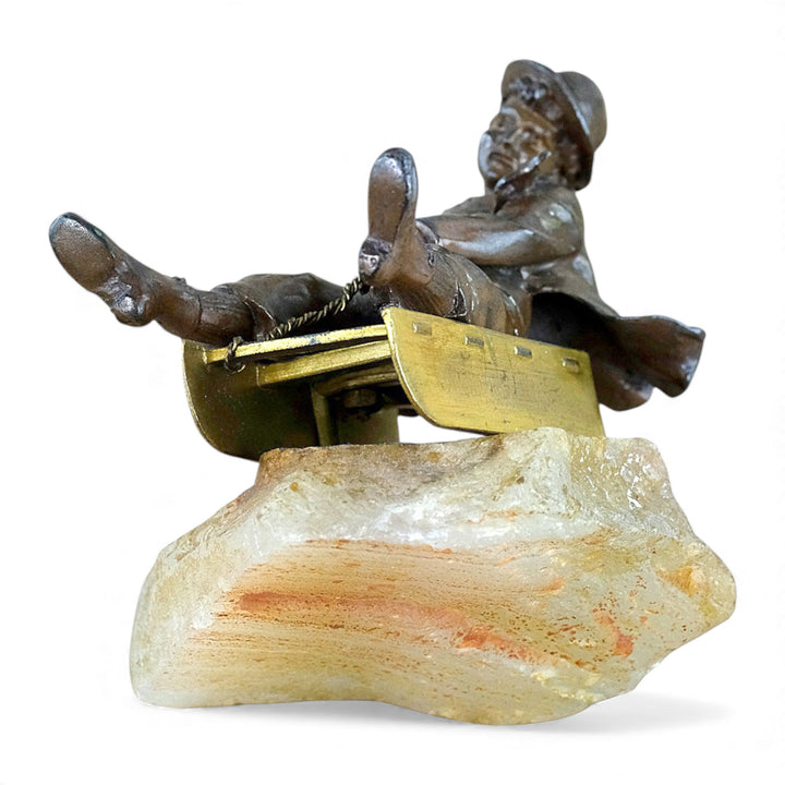 Escultura antigua de bronce de un niño en un trineo.