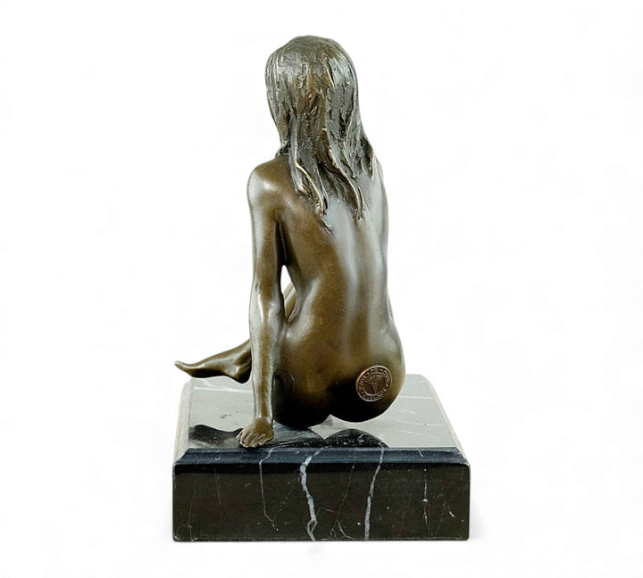 Escultura de bronce de una mujer desnuda coqueta