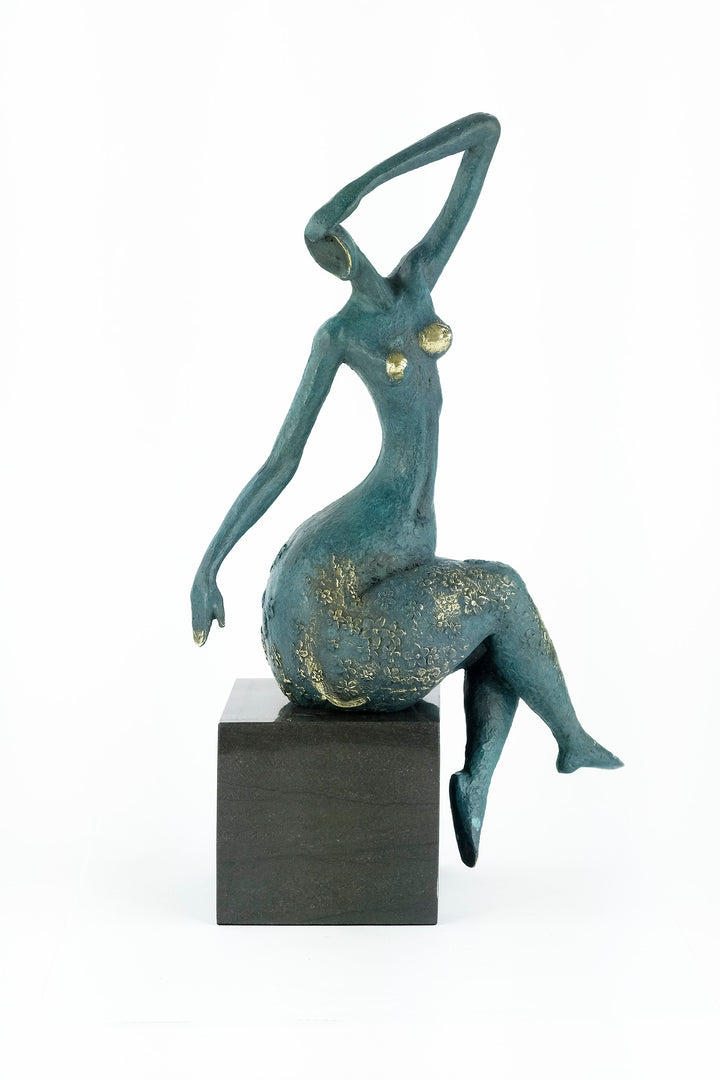 Modern bronze sculpture of a female sitting in a graceful pose