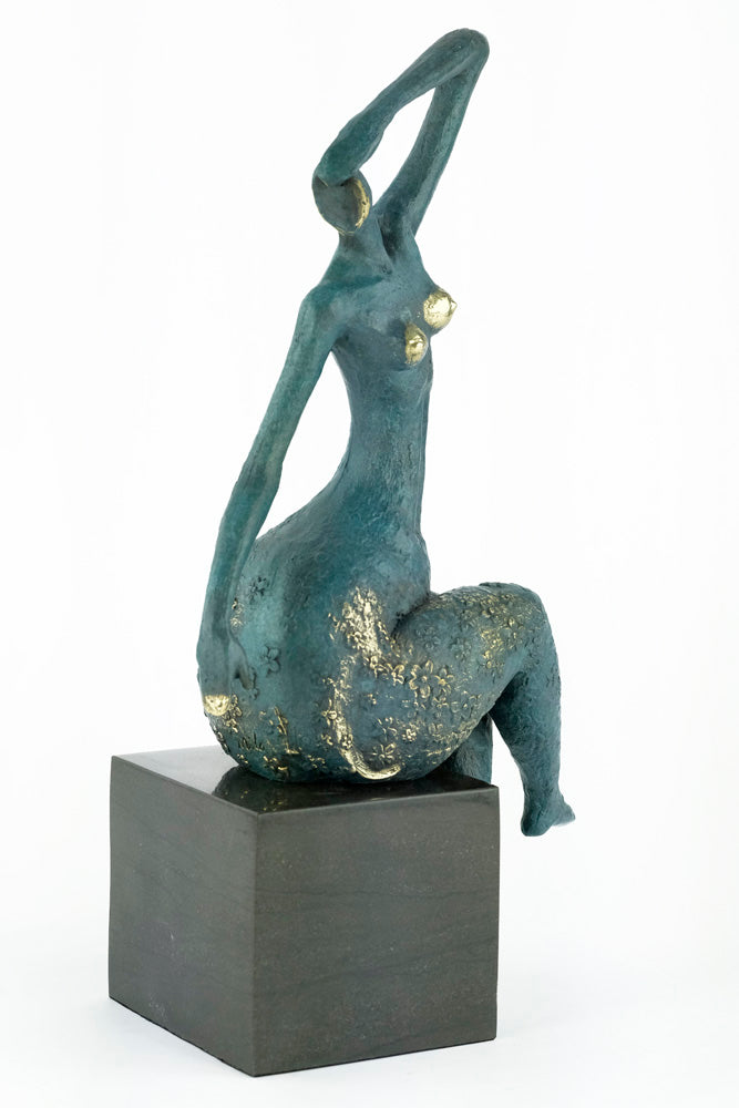 Modern bronze sculpture of a female sitting in a graceful pose