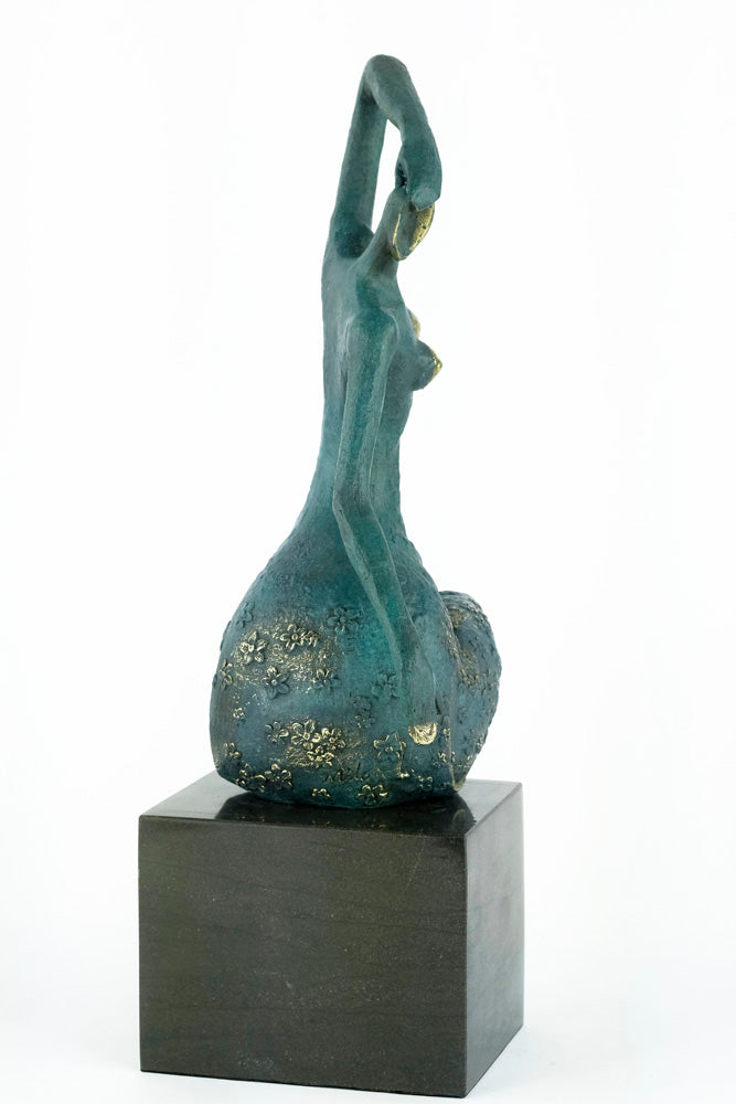 Modern bronze sculpture of a female sitting in a graceful pose