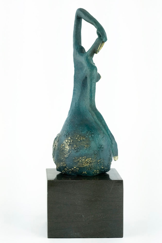 Modern bronze sculpture of a female sitting in a graceful pose