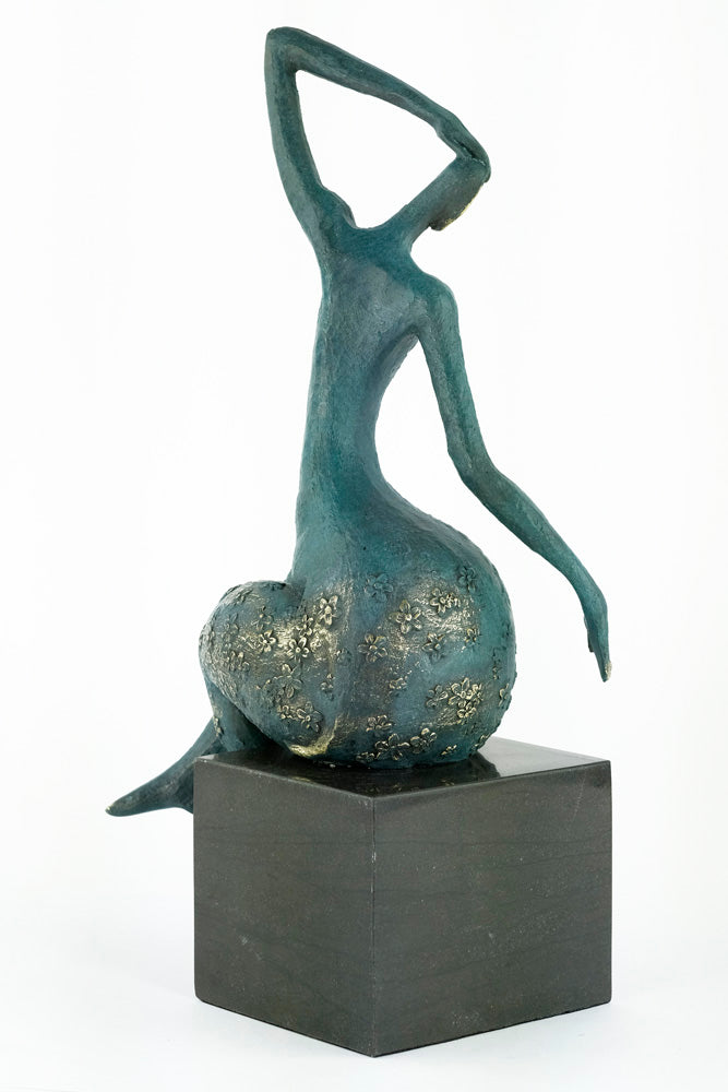 Modern bronze sculpture of a female sitting in a graceful pose