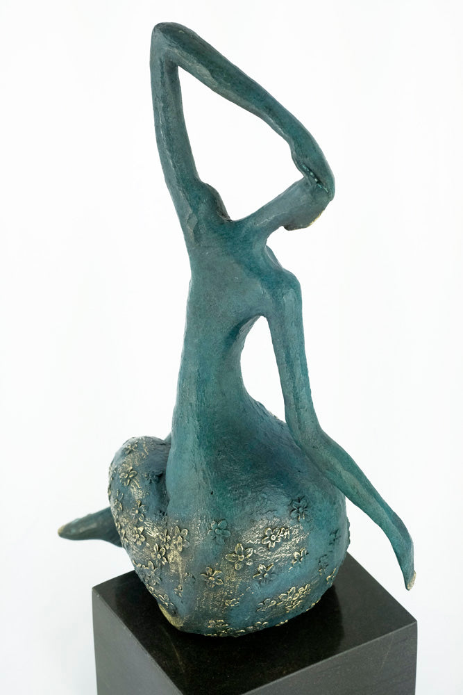 Modern bronze sculpture of a female sitting in a graceful pose