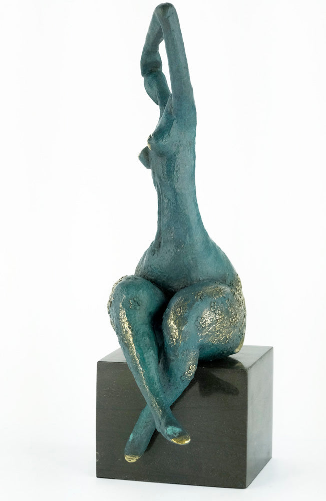 Modern bronze sculpture of a female sitting in a graceful pose