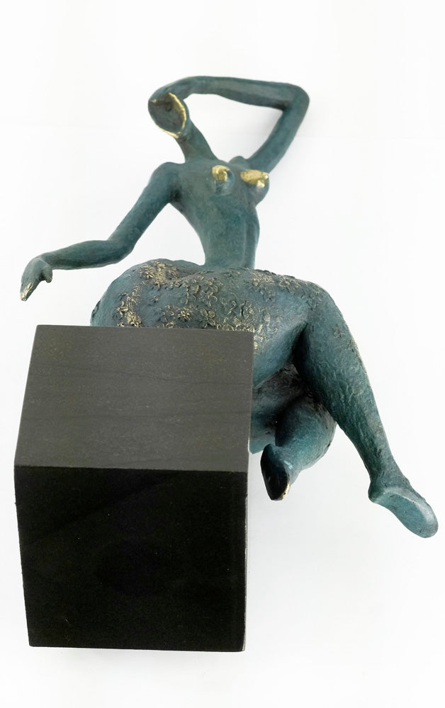 Modern bronze sculpture of a female sitting in a graceful pose