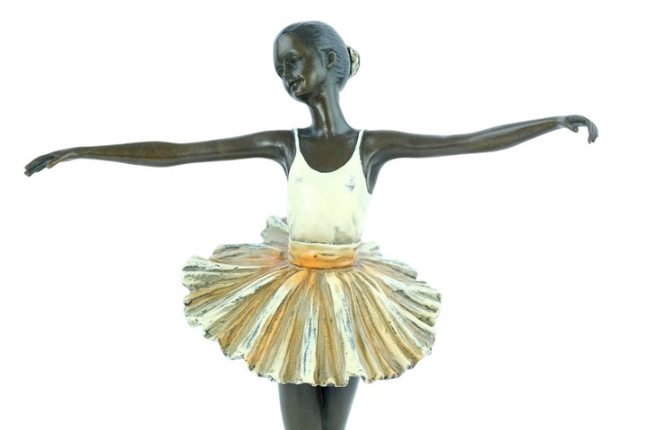 Bronze sculpture of a ballerina standing tip-toe wearing a white tutu