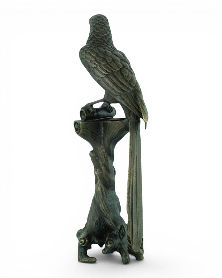 Bronze sculpture of a macaw sitting on a tree trunk