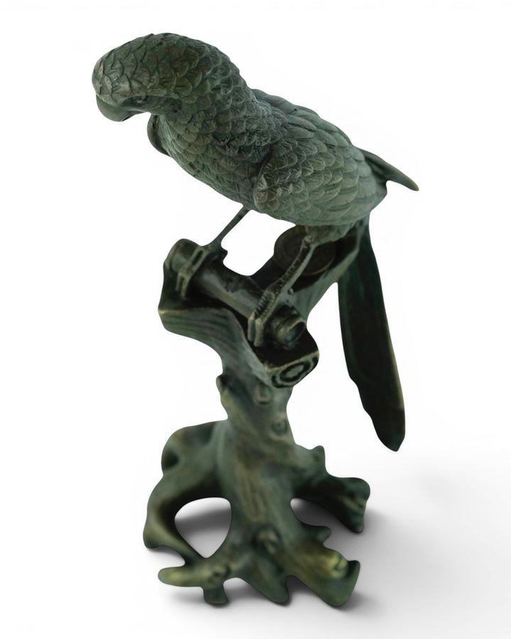 Bronze sculpture of a macaw sitting on a tree trunk