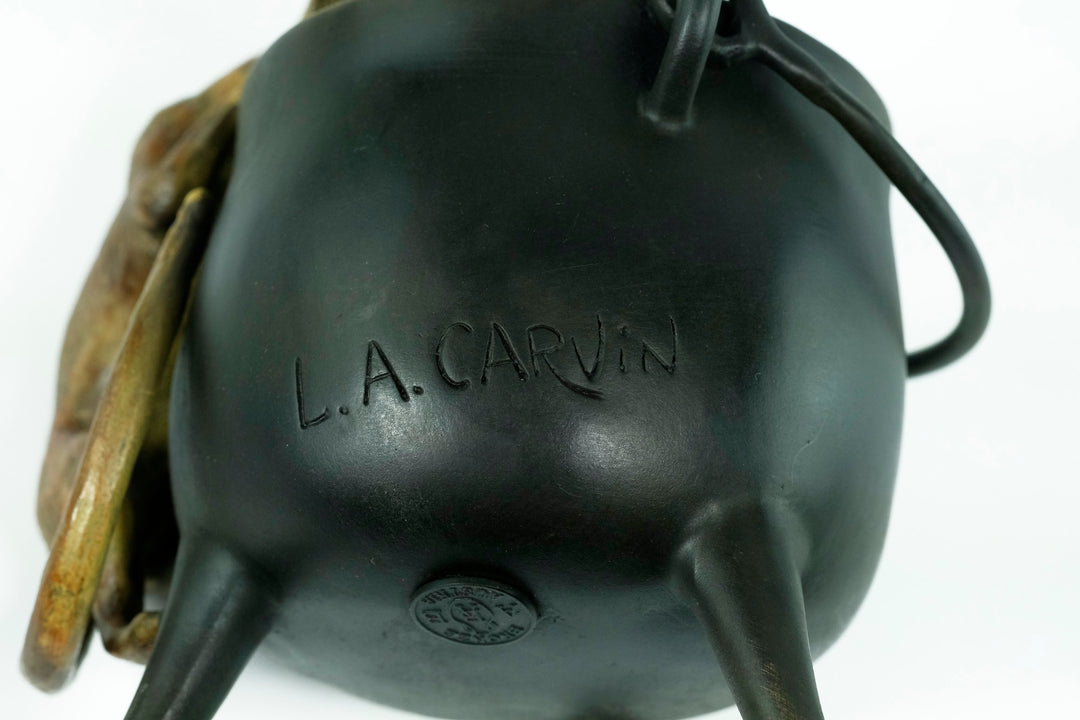 Bronze sculpture of a curious cat climbing into a cauldron