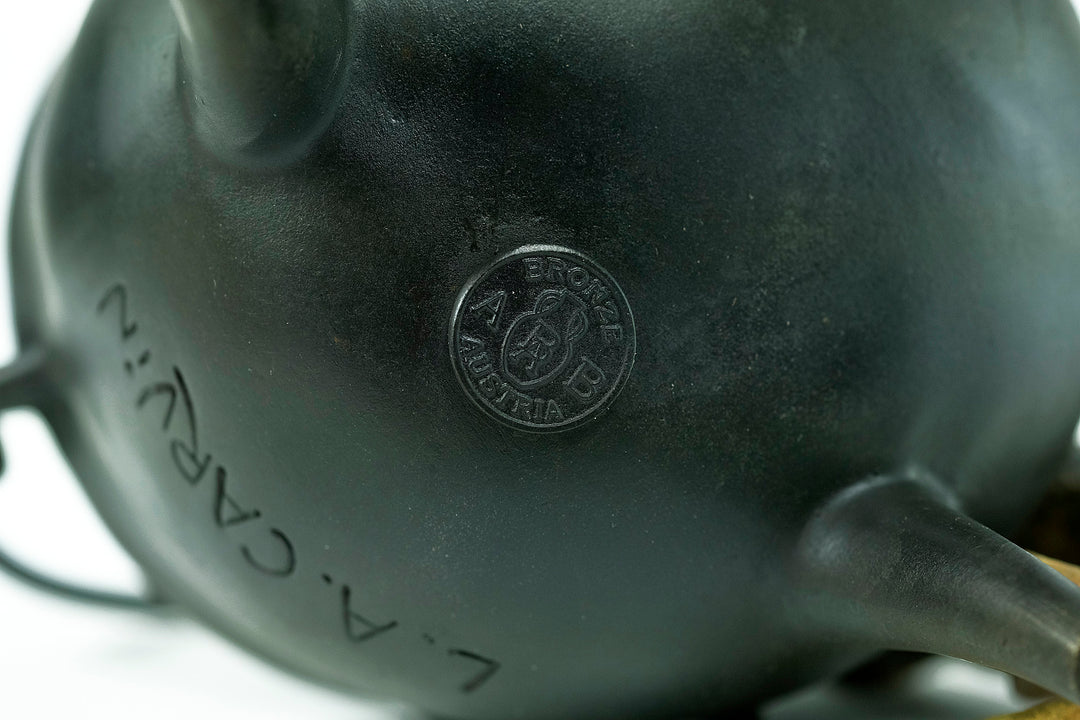 Bronze sculpture of a curious cat climbing into a cauldron