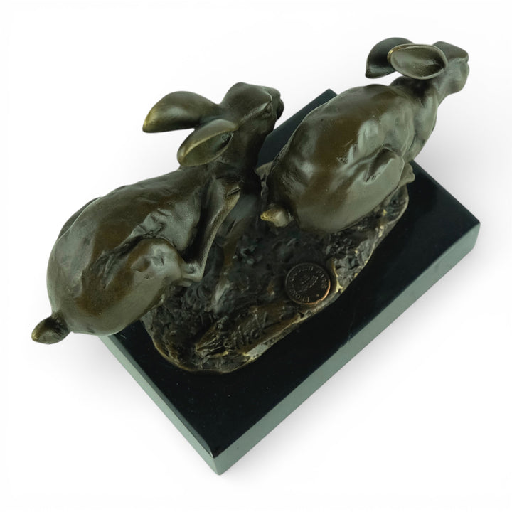 Escultura de bronce de dos liebres corriendo