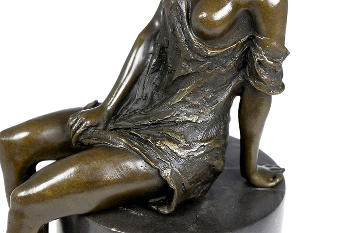 Bronze sculpture of a sitting female in flimsy dress