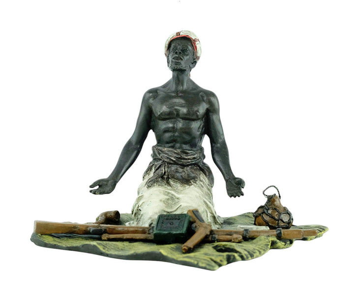 Bronze sculpture of an Arabian male on a rug selling weapons