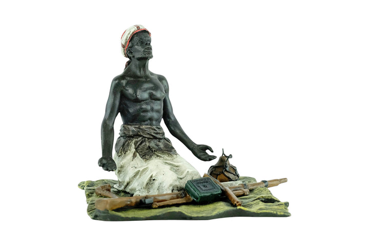 Bronze sculpture of an Arabian male on a rug selling weapons