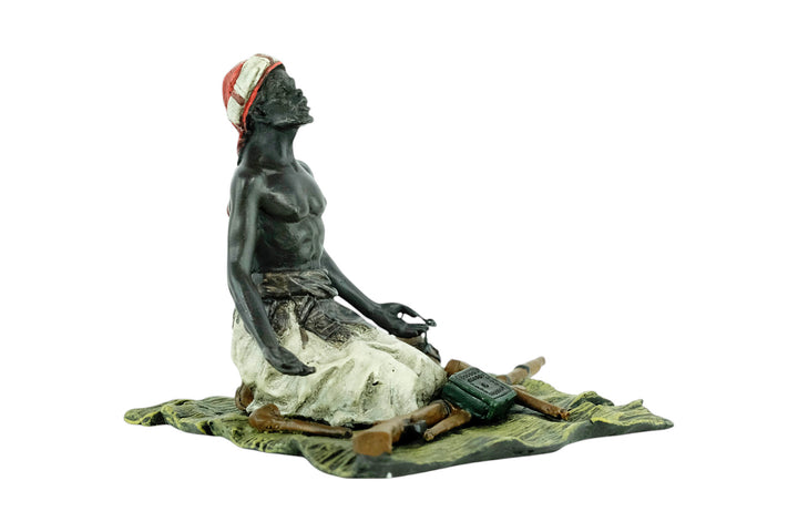 Bronze sculpture of an Arabian male on a rug selling weapons