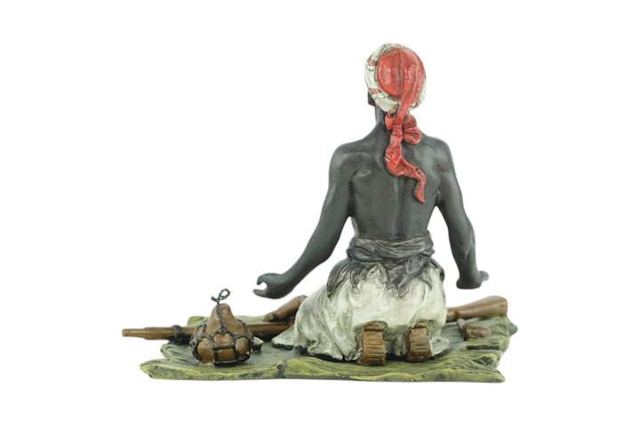 Bronze sculpture of an Arabian male on a rug selling weapons