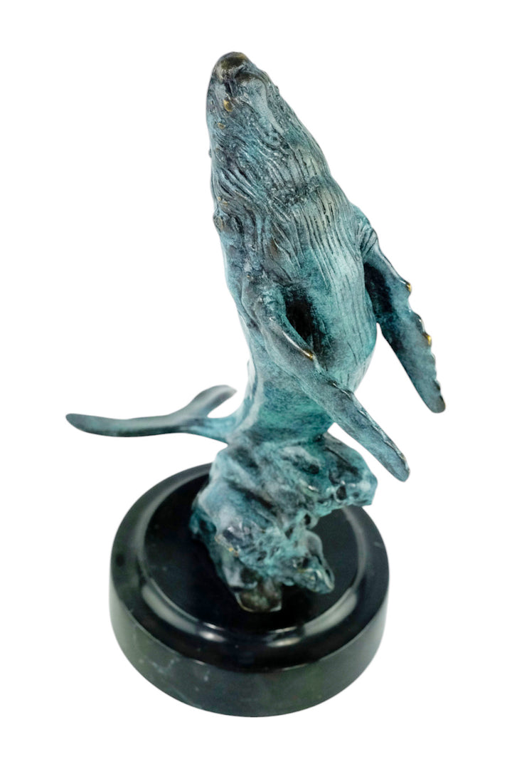 Bronze sculpture of a humpback whale breaching the surface