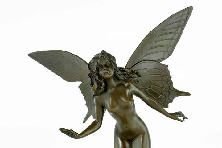 Bronze sculpture of a winged fairy standing on a tree trunk