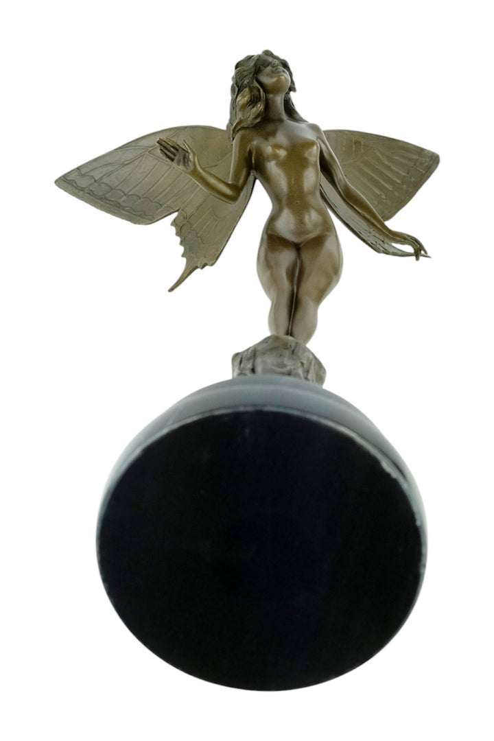 Bronze sculpture of a winged fairy standing on a tree trunk