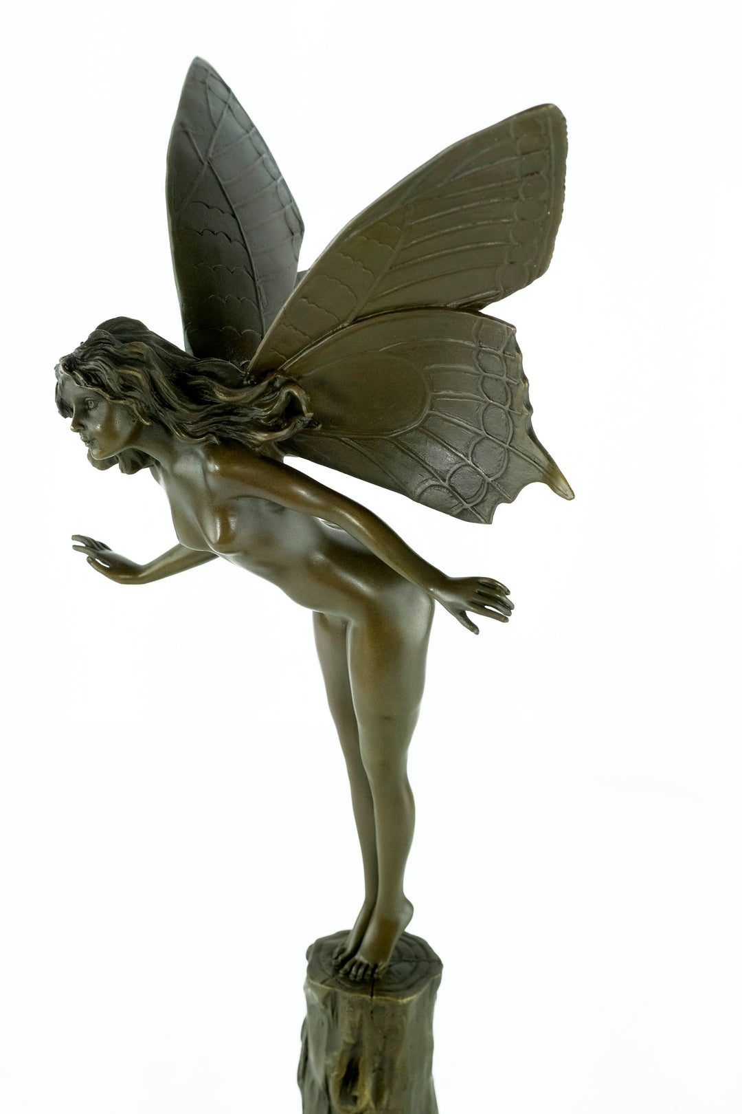 Bronze sculpture of a winged fairy standing on a tree trunk
