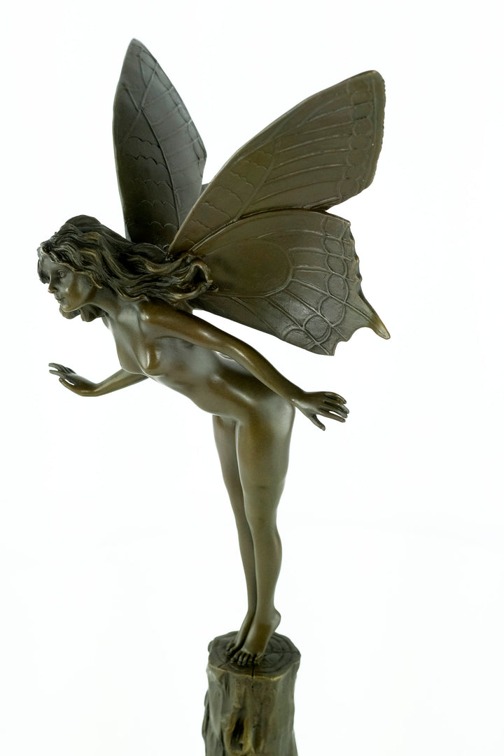 Bronze sculpture of a winged fairy standing on a tree trunk
