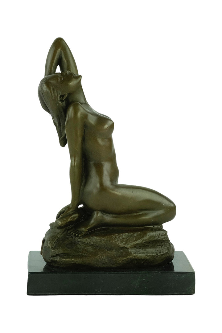 Bronze sculpture of a sensual female nude kneeling on a rock
