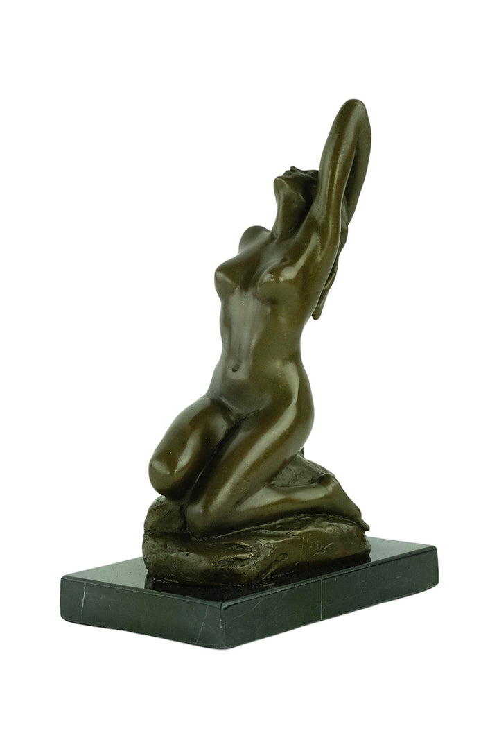 Bronze sculpture of a sensual female nude kneeling on a rock