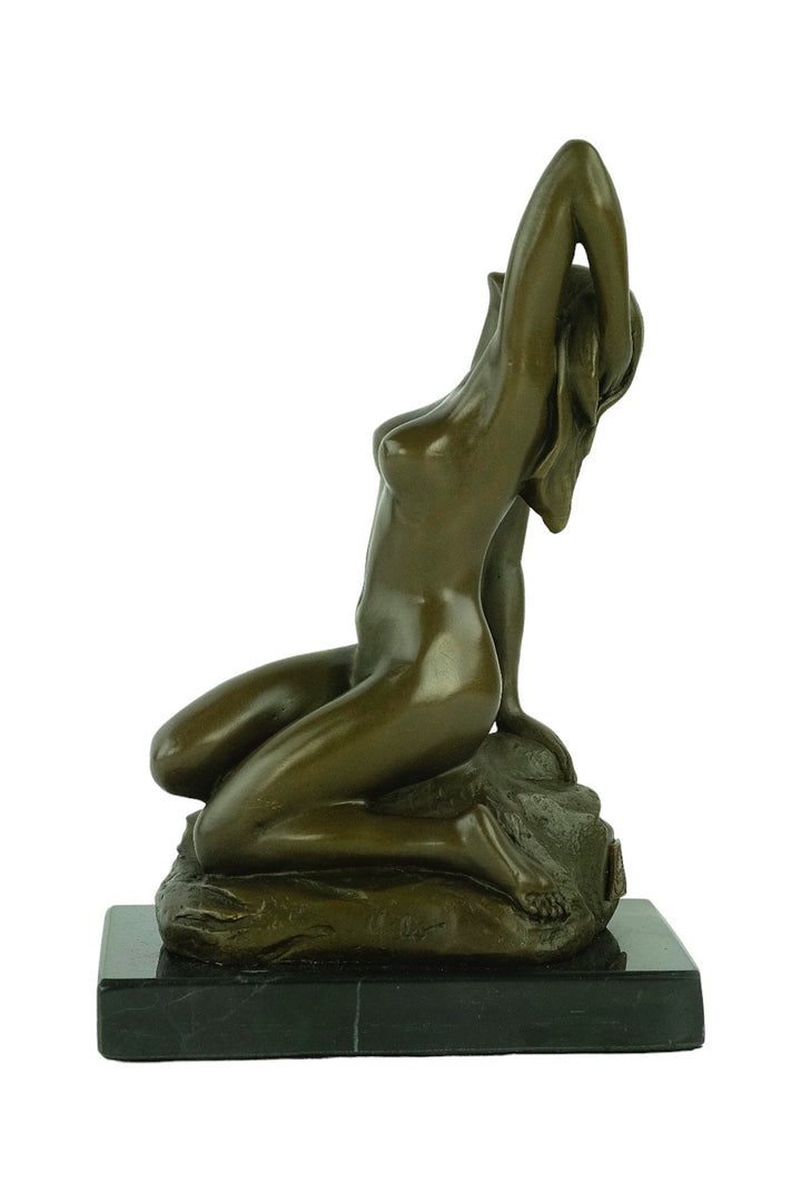 Bronze sculpture of a sensual female nude kneeling on a rock