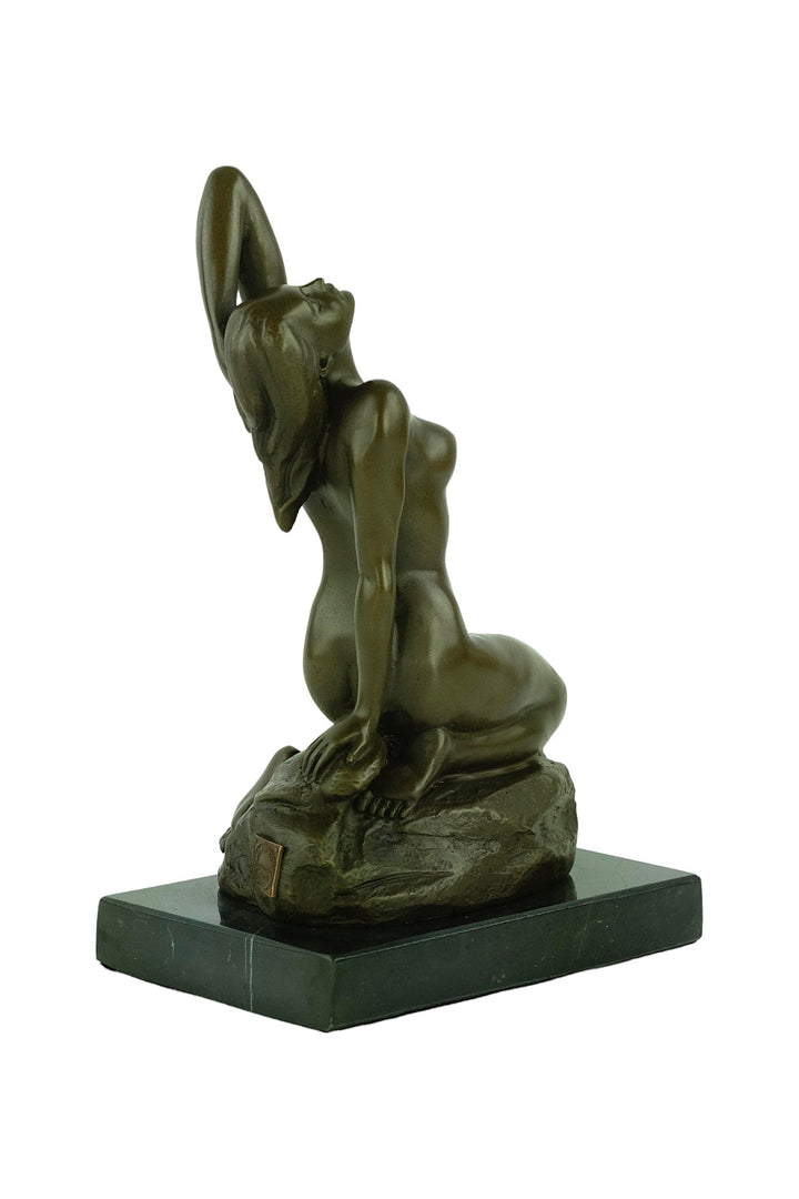 Bronze sculpture of a sensual female nude kneeling on a rock