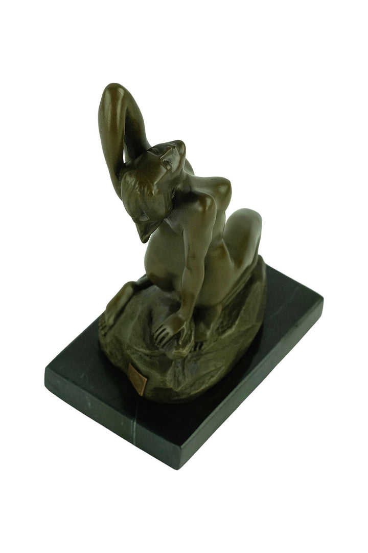 Bronze sculpture of a sensual female nude kneeling on a rock