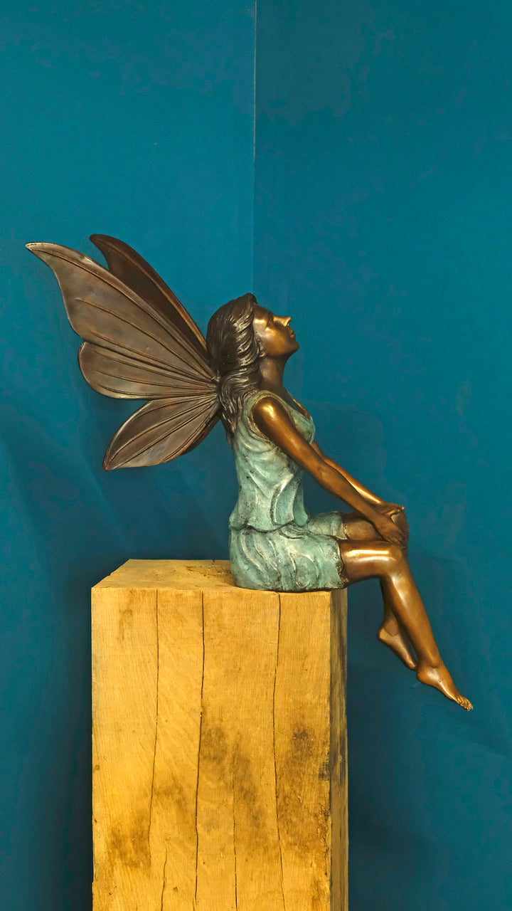 Bronze sculpture of a sitting winged fairy