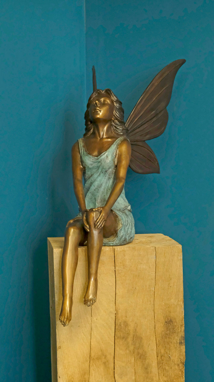 Bronze sculpture of a sitting winged fairy
