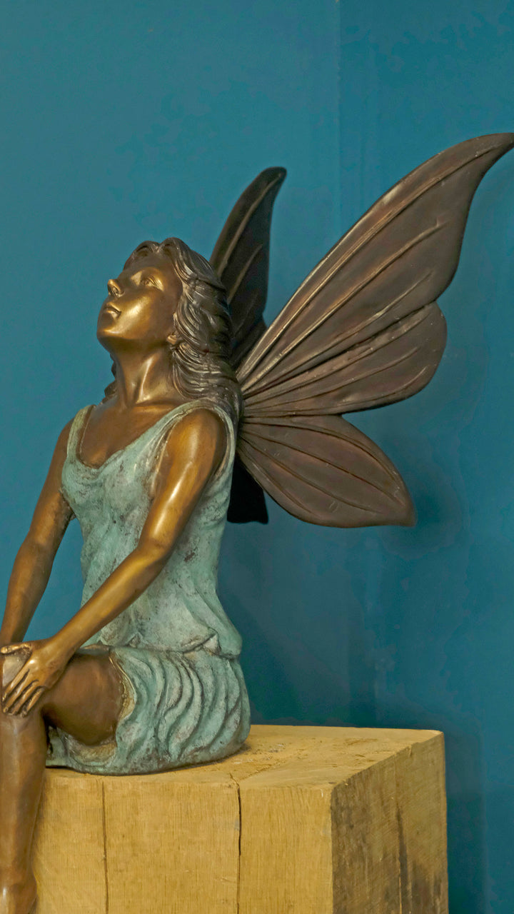 Bronze sculpture of a sitting winged fairy