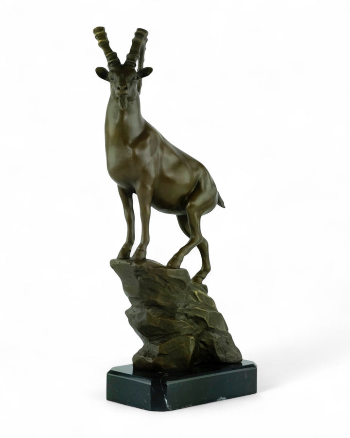 Bronze sculpture of an ibex on a rock