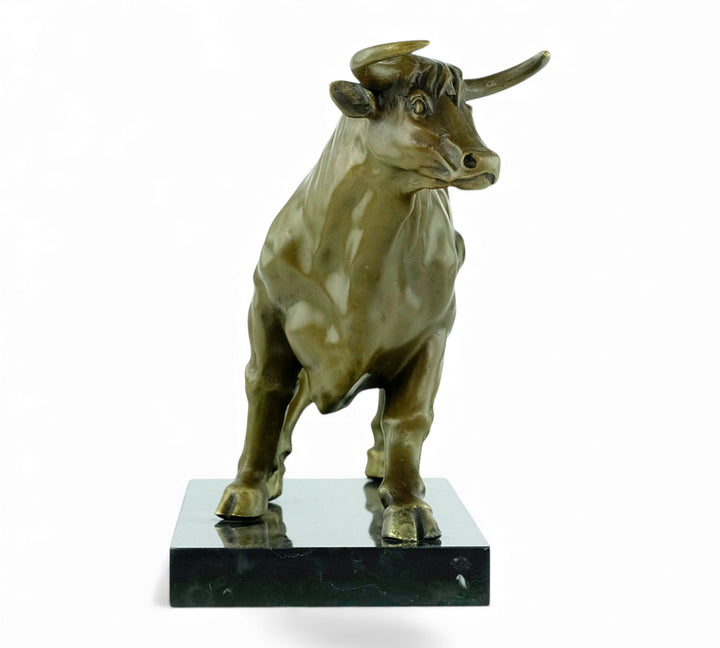 Escultura de bronce de un toro feroz sobre una meseta de mármol