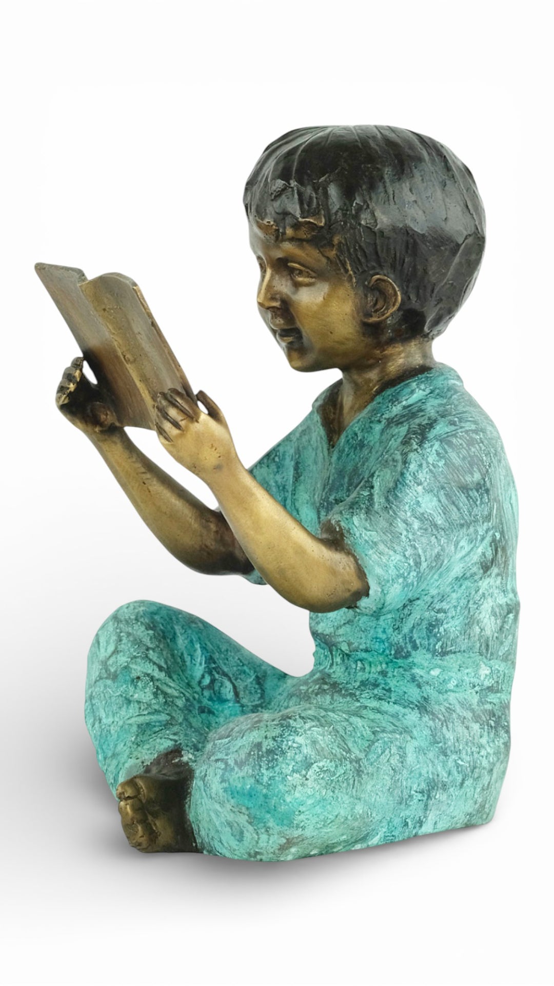 Escultura de bronce de un joven sentado leyendo un libro