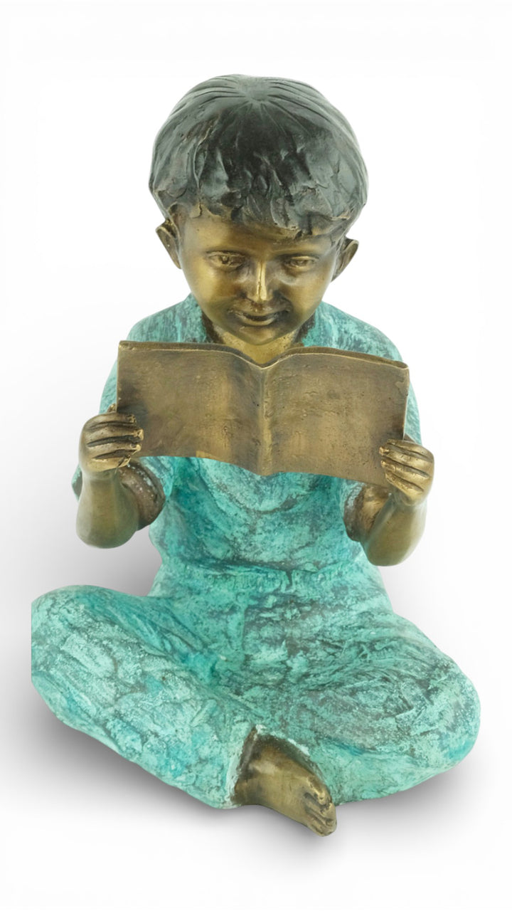 Escultura de bronce de un joven sentado leyendo un libro