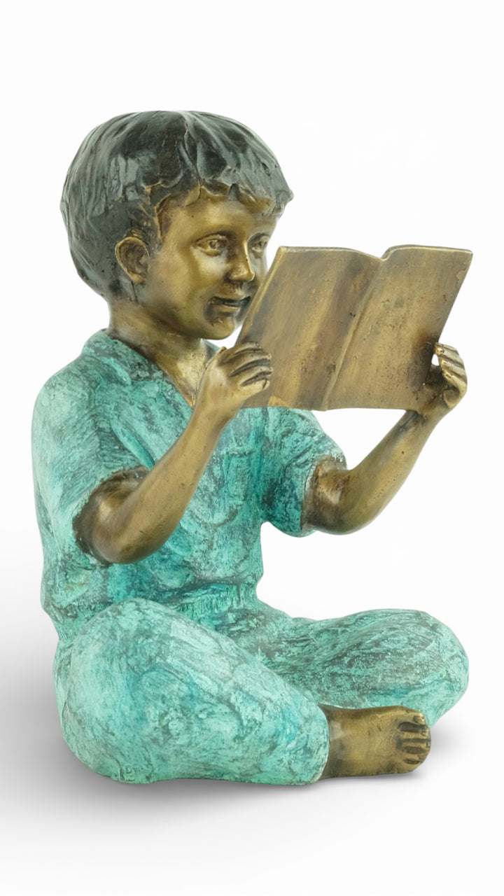 Escultura de bronce de un joven sentado leyendo un libro