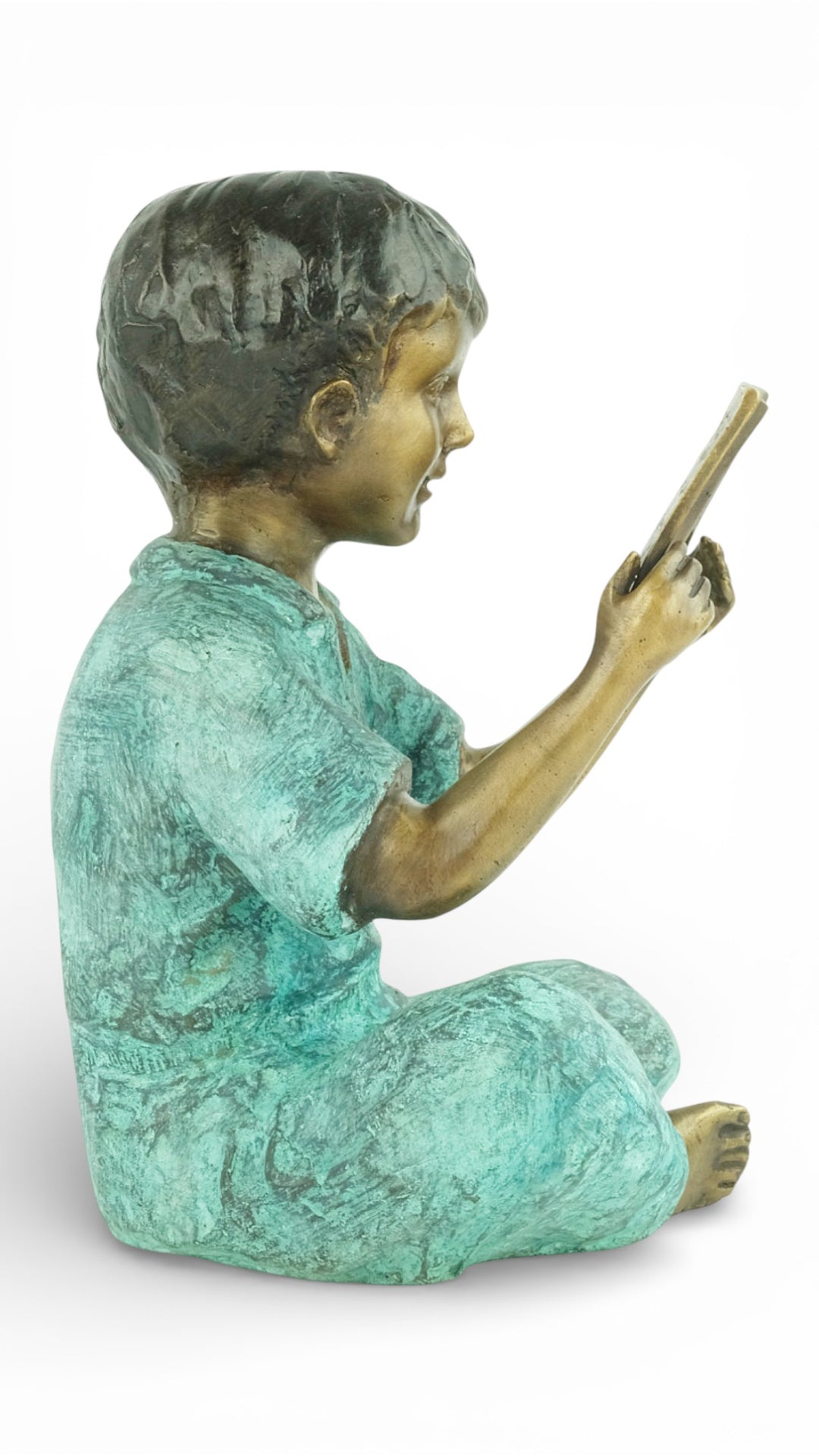 Escultura de bronce de un joven sentado leyendo un libro