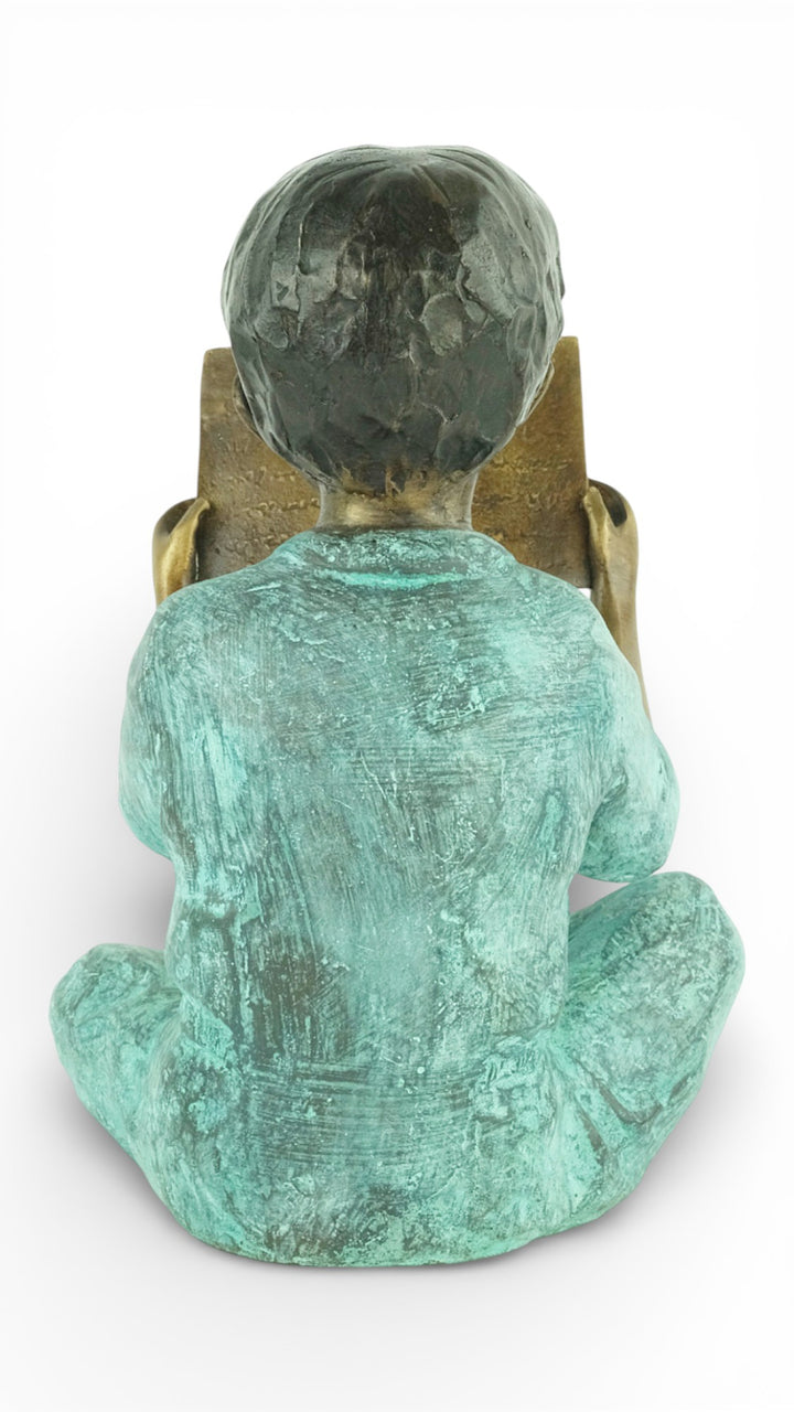 Escultura de bronce de un joven sentado leyendo un libro
